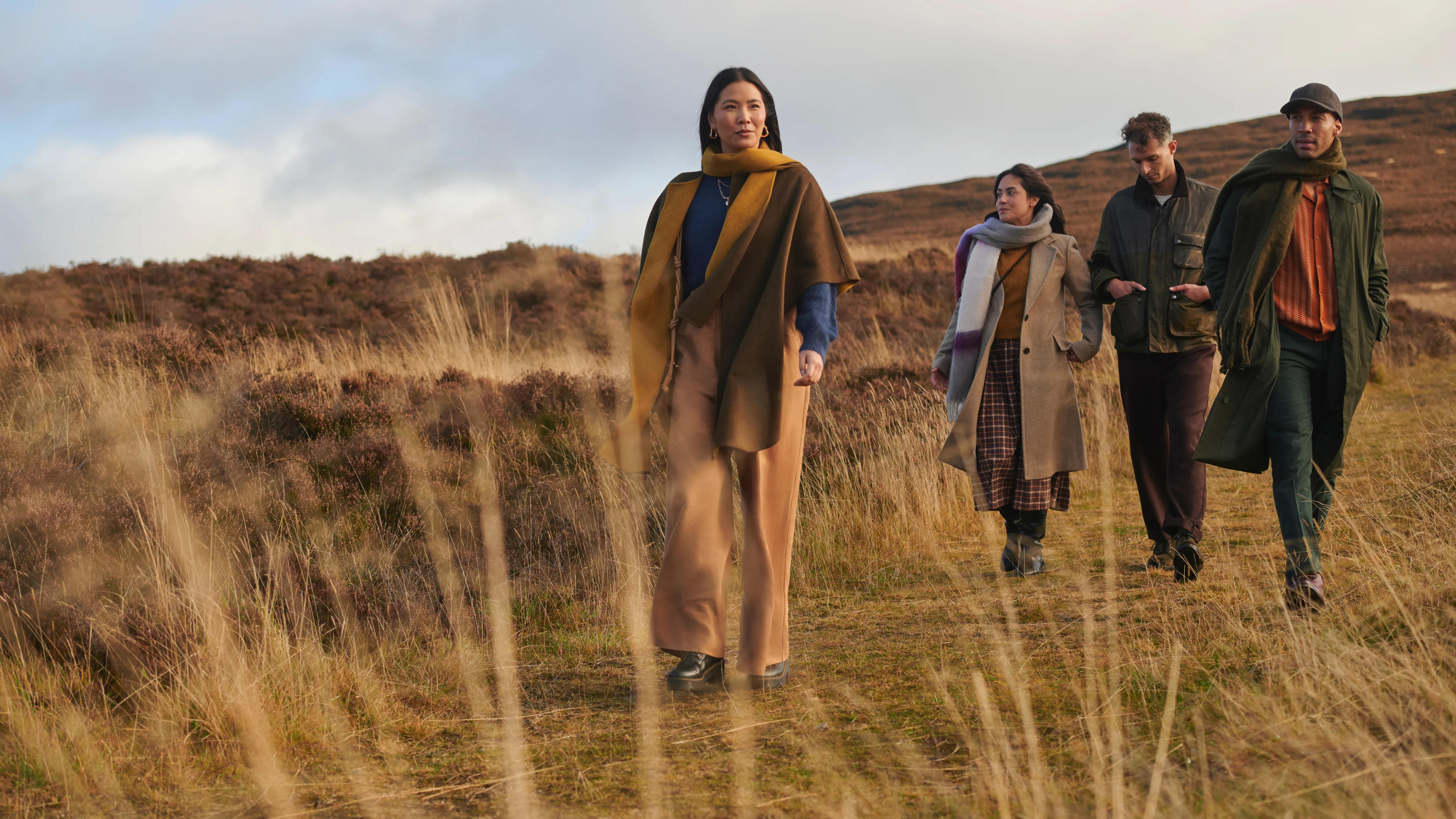 People walking through grassy landscape during a whisky distillery trip in Scotland.
