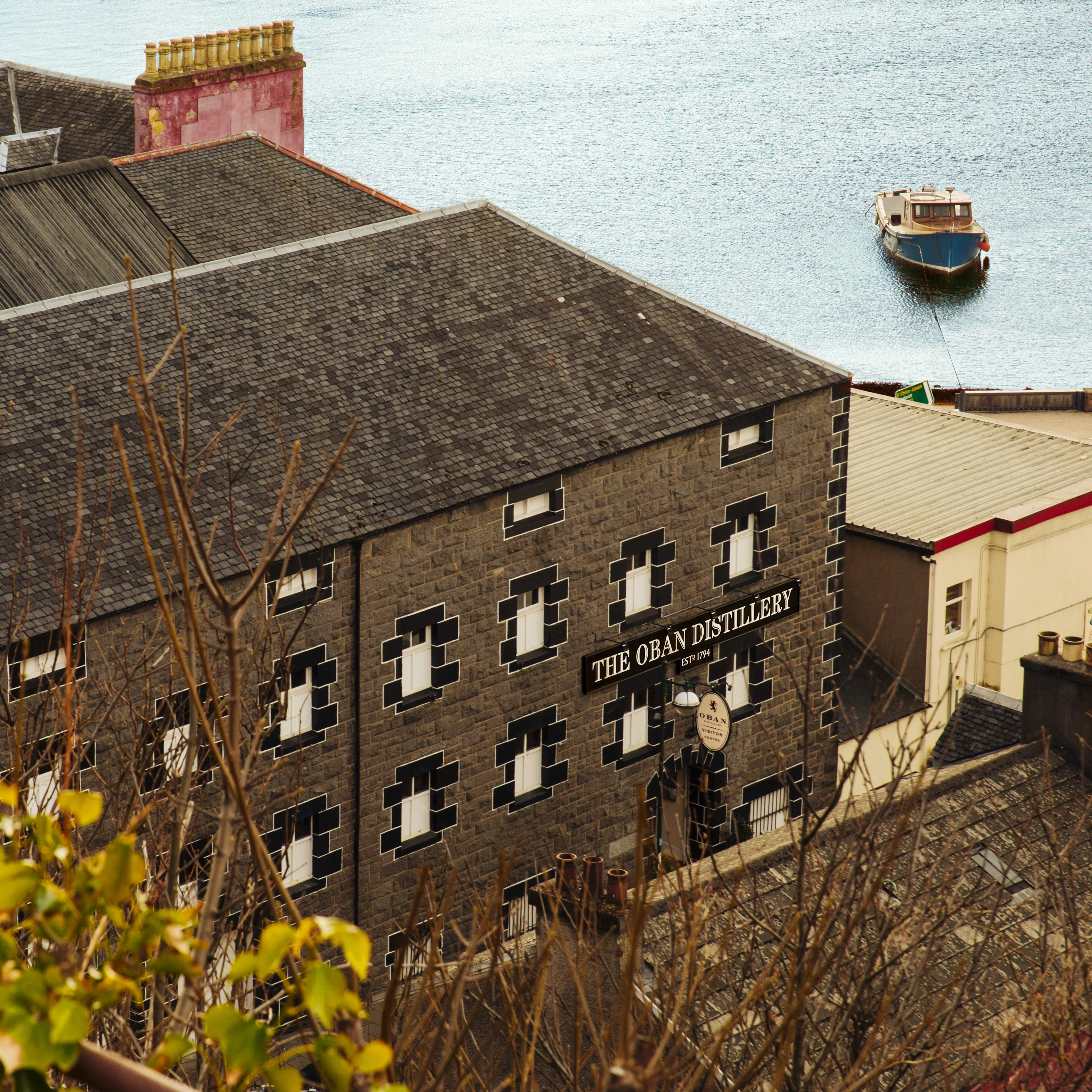 Das Äußere eines Steingebäudes mit der Aufschrift "Oban Distillery", direkt am Meer.