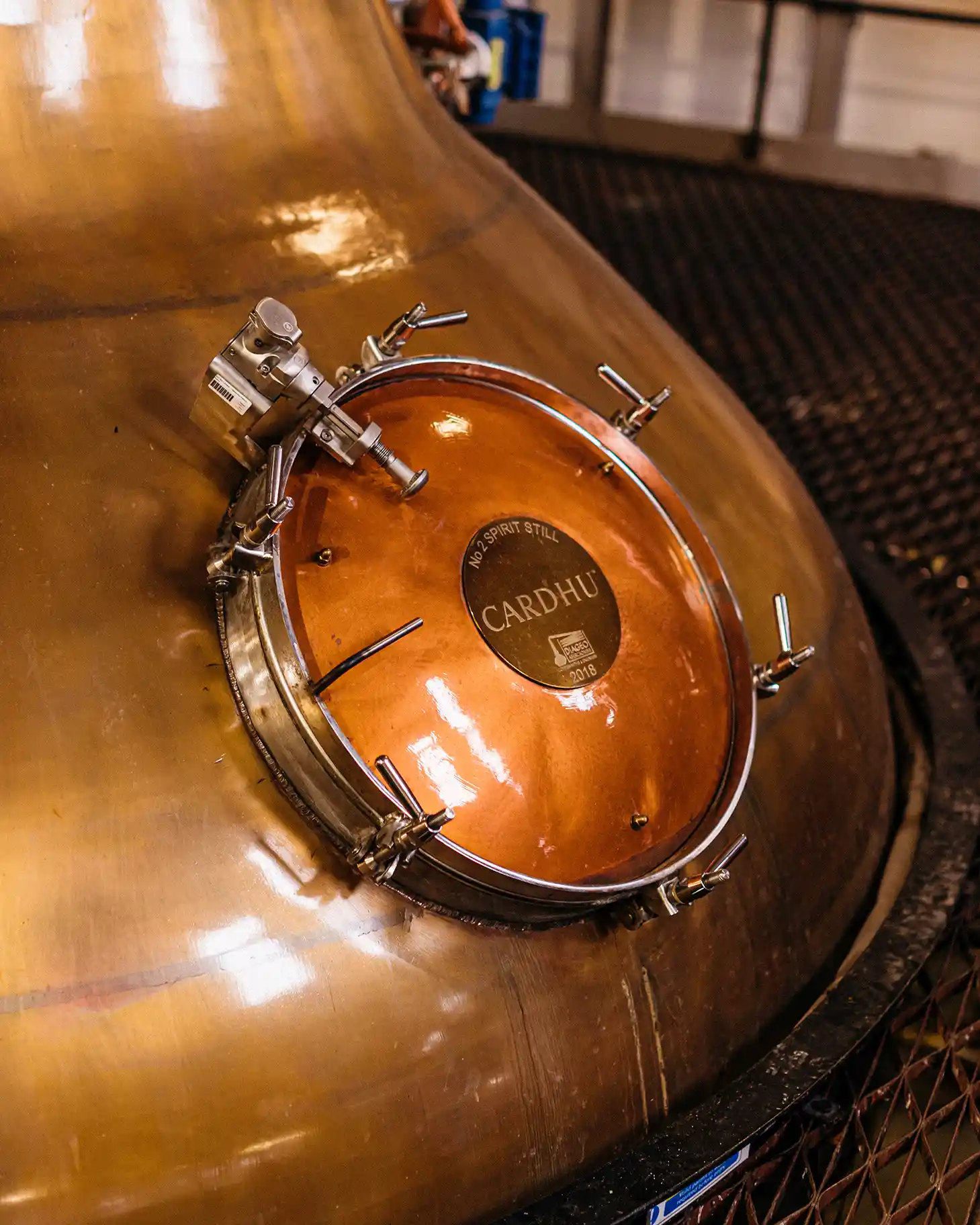  A metal whisky still is pictured with a metal plaque which displays the word ‘Cardhu’.