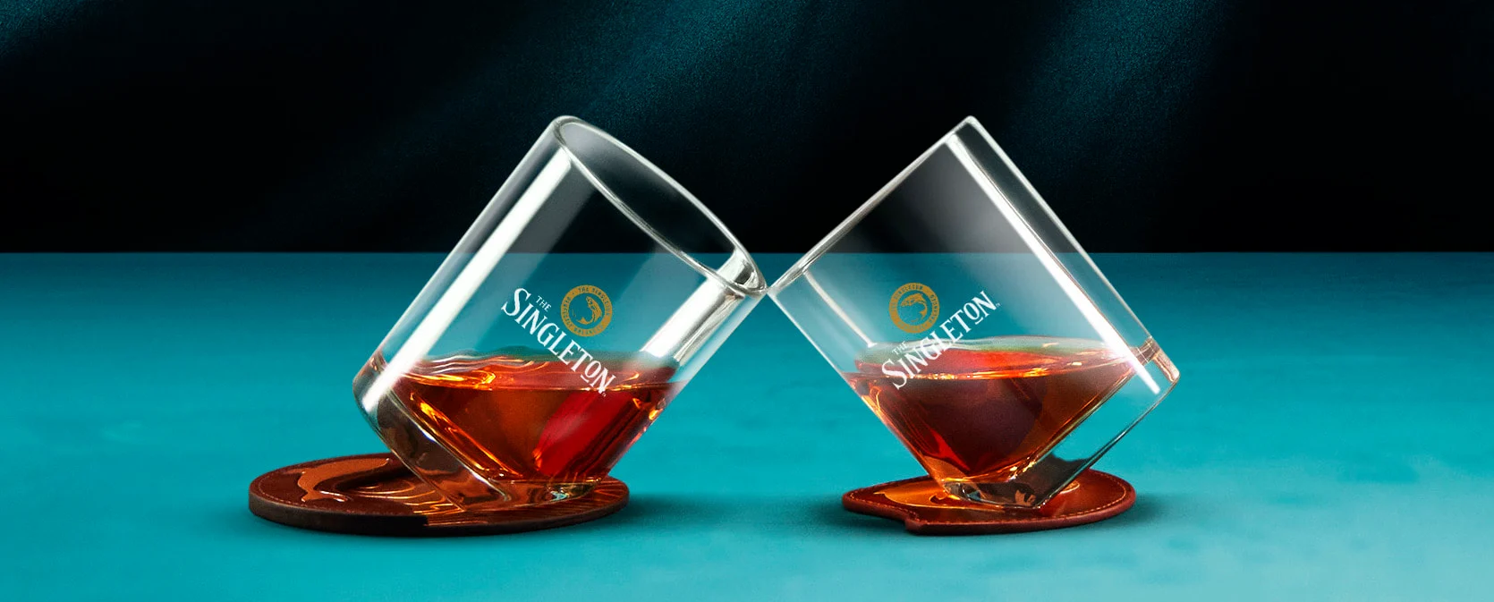 兩小瓶12年單一麥芽威士忌The Singleton Glen Ord雪莉桶，傾斜放置在藍色表面的杯墊上。