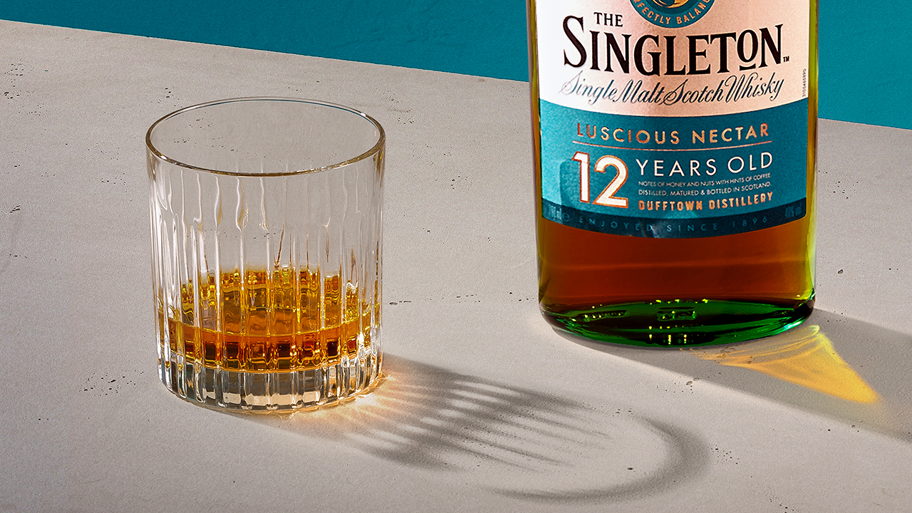 A glass of whisky next to a bottle of The Singleton 12 Year Old Single Malt Scotch Whisky.