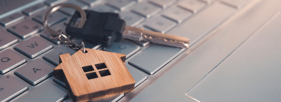 Mortgage concept with keys and house-shaped key ring on laptop keyboard