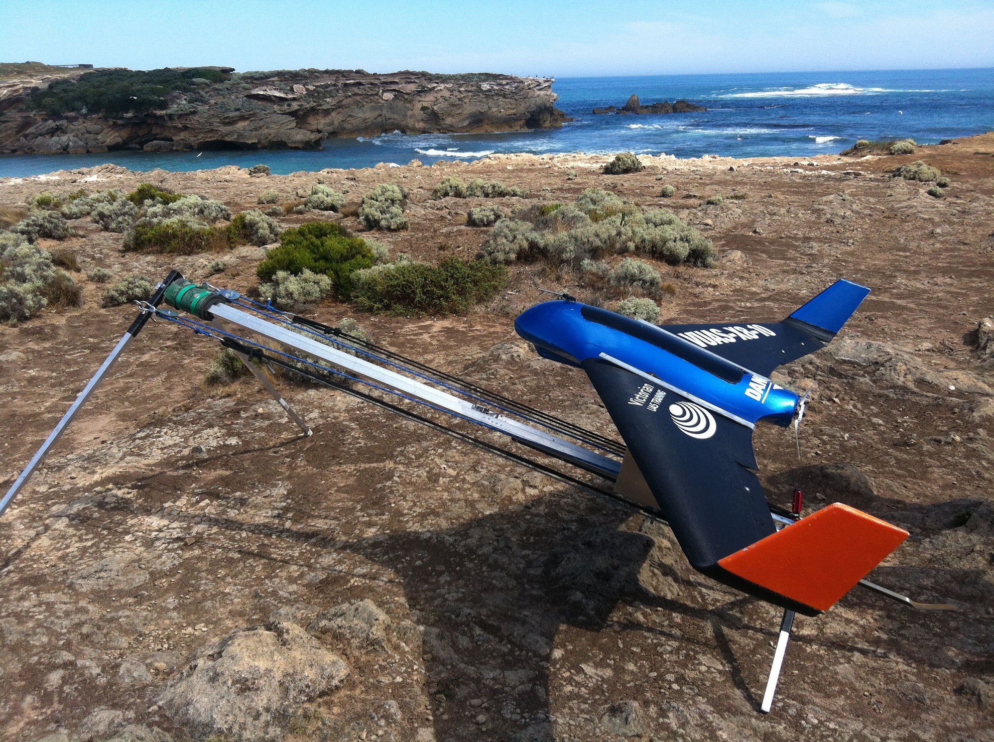 A fixed-wing drone ready for takeoff from a clifftop.