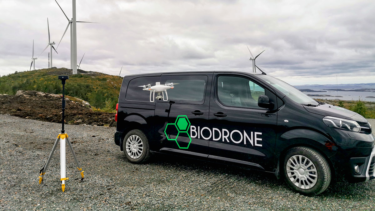 Biodrone black car with wind turbines in background