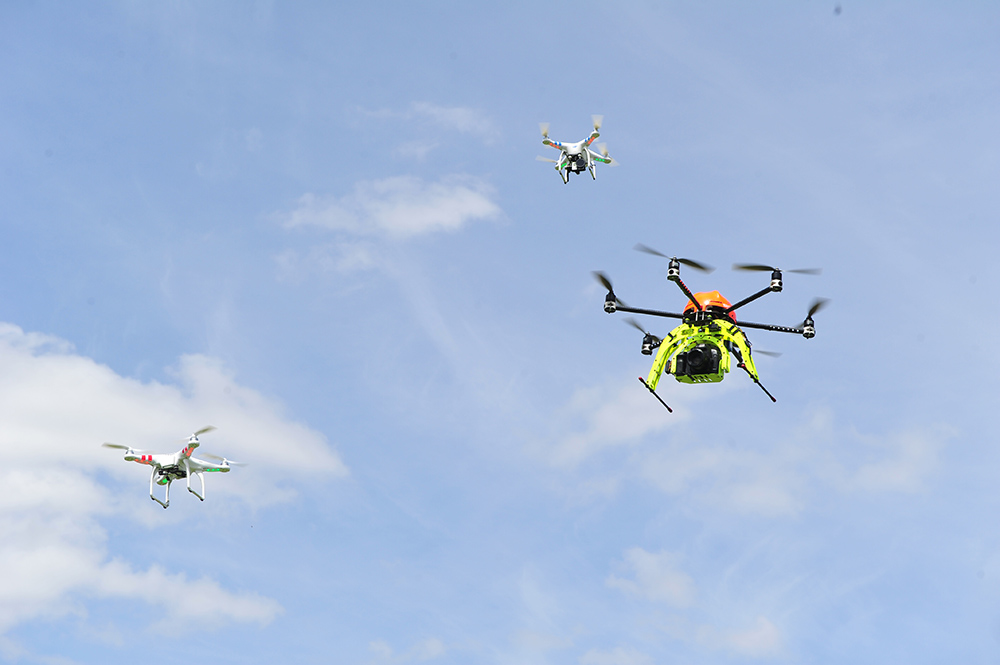 Three drones flying through a blue sky