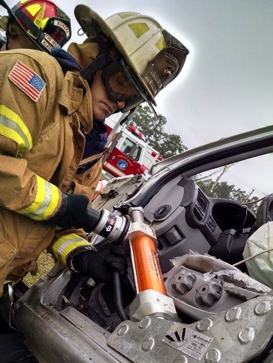 A first responder works on prying open a door of a crash scene.