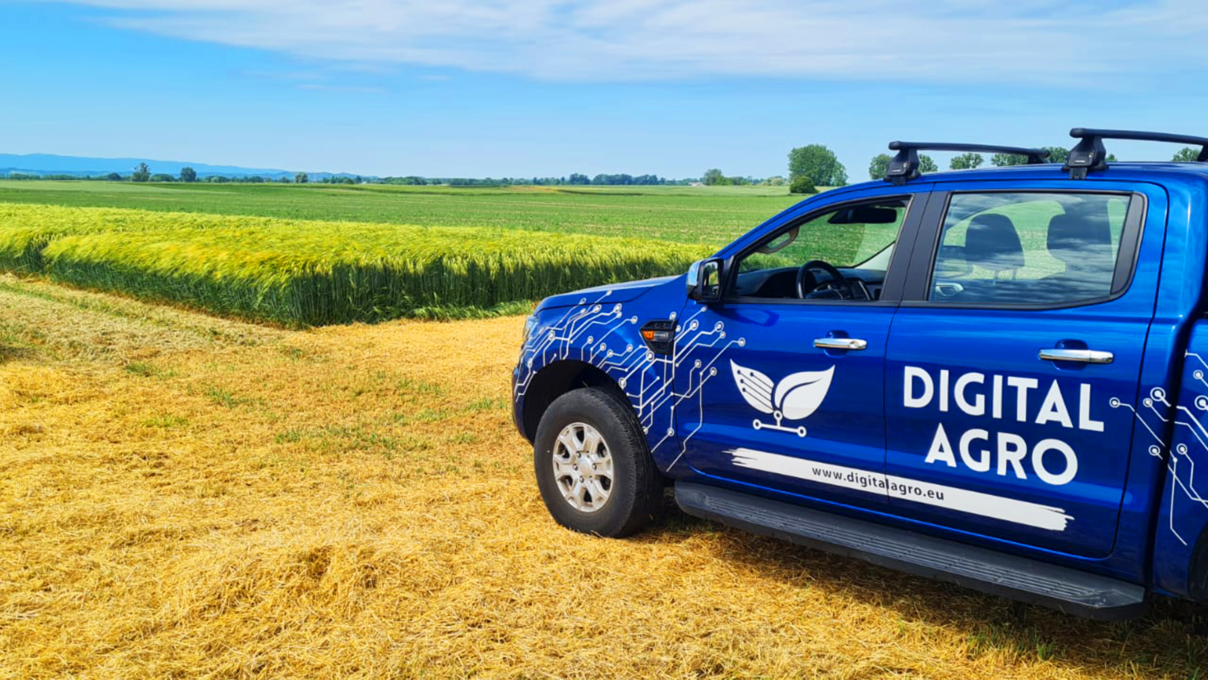 Blue pick up turck in a wheat field with Digital Agro written on the side