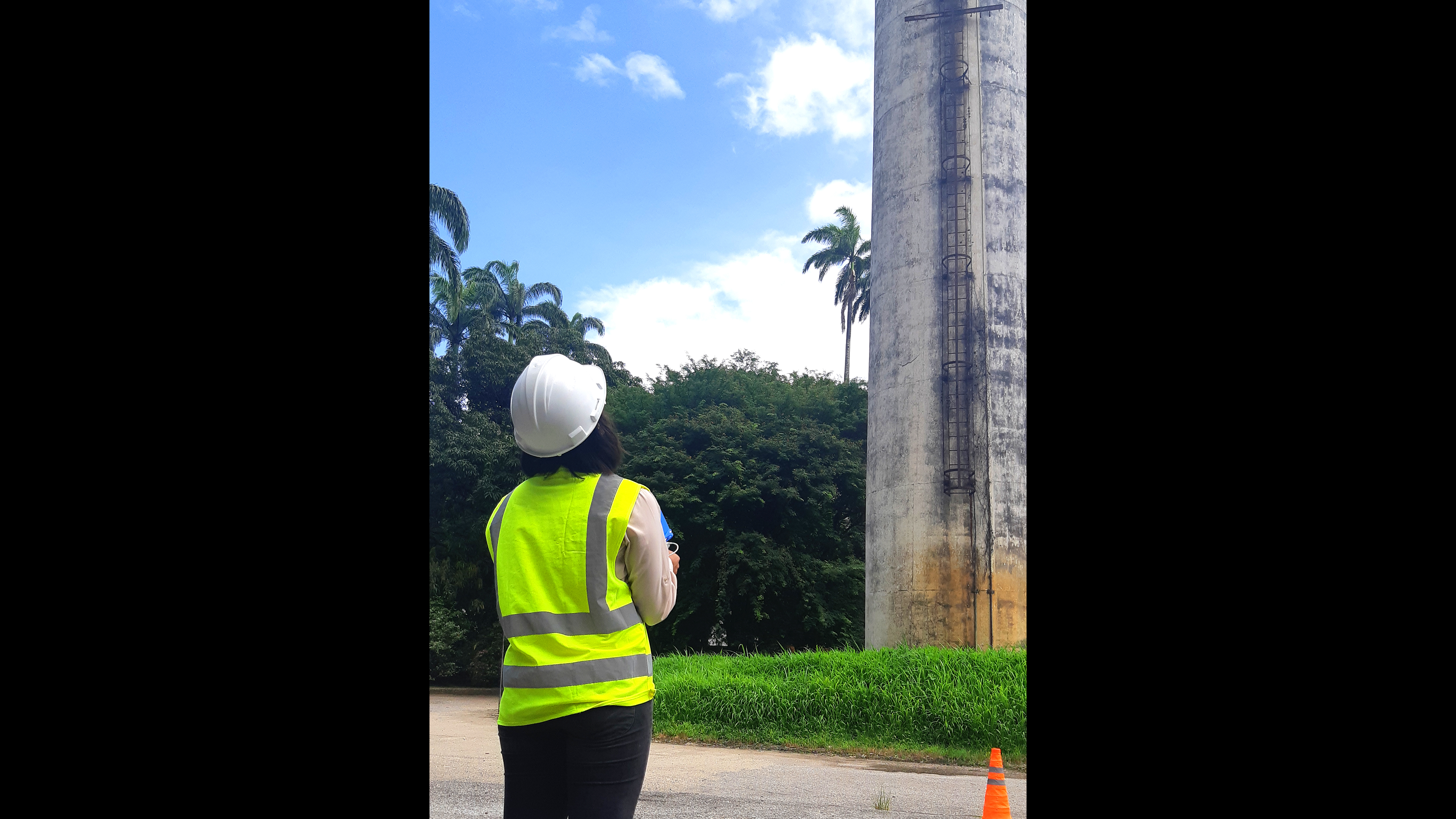 Drone pilot in a high vis jacket looking up at a chimney