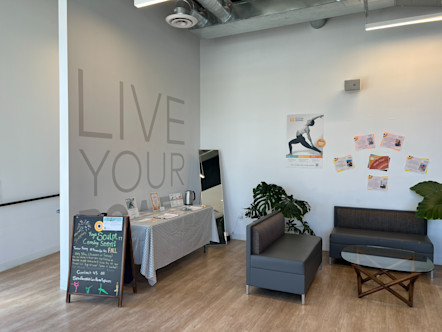 Rockridge studio lobby with dark gray couches adjacent to a white pocket wall with a 'Live Your Power' text graphic