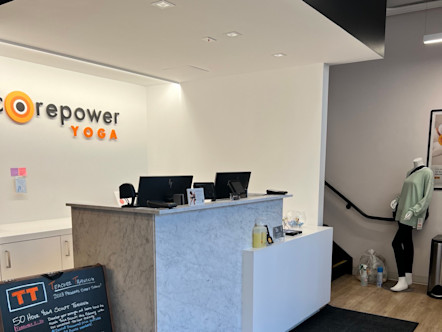 CorePower Yoga Cow Hollow studio's white and marble front desk with monitors and Teacher Training signage