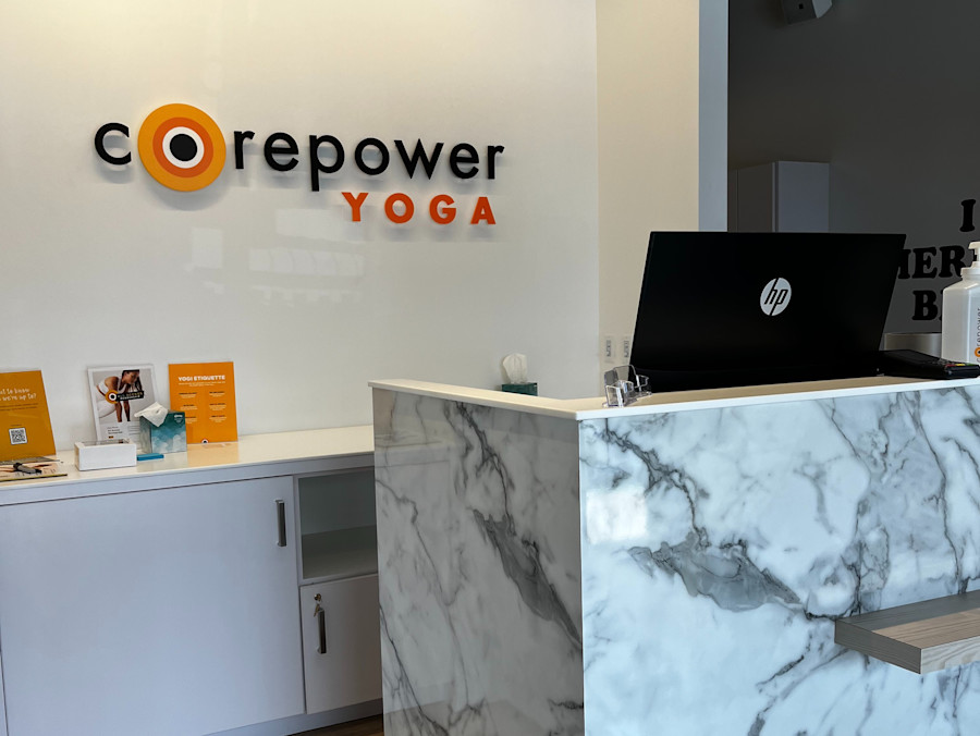 The front desk at CorePower Yoga Hermosa Beach, marble counter beneath the studio's wall logo