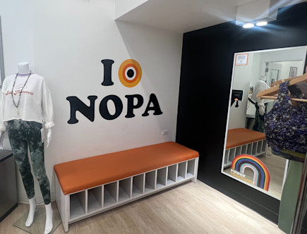 Orange 'I love NOPA' decal displayed over a plush orange and white bench for storing yoga gear