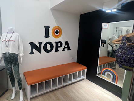 Orange 'I love NOPA' decal displayed over a plush orange and white bench for storing yoga gear