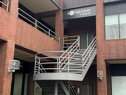 Black CorePower Yoga sign on the second story of a red brick building with a silver split staircase leading up to its entrance
