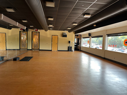 CPY studio room with floor to ceiling front mirrors, black ceiling pipes and tiles, and a back wall lined with windows