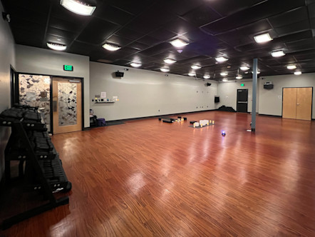 CPY studio room with medium wash cherry-brown wooden floors, black paneled ceilings, and tannish-grey colored walls