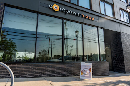 CorePower Yoga storefront with large glass windows and a sidewalk sign reading “Now Open” in front
