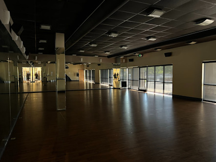 Dimly lit Mission Viejo practice room with dark brown wooden floors and pale yellow/mirrored walls