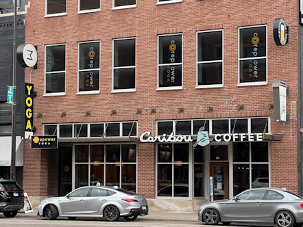 CorePower Yoga signage in the second story windows of a red brick building above a Caribou Coffee shop