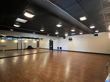 Westlake Village CPY studio room with medium tan wooden floors, floor to ceiling front mirrors, and black tiled ceilings