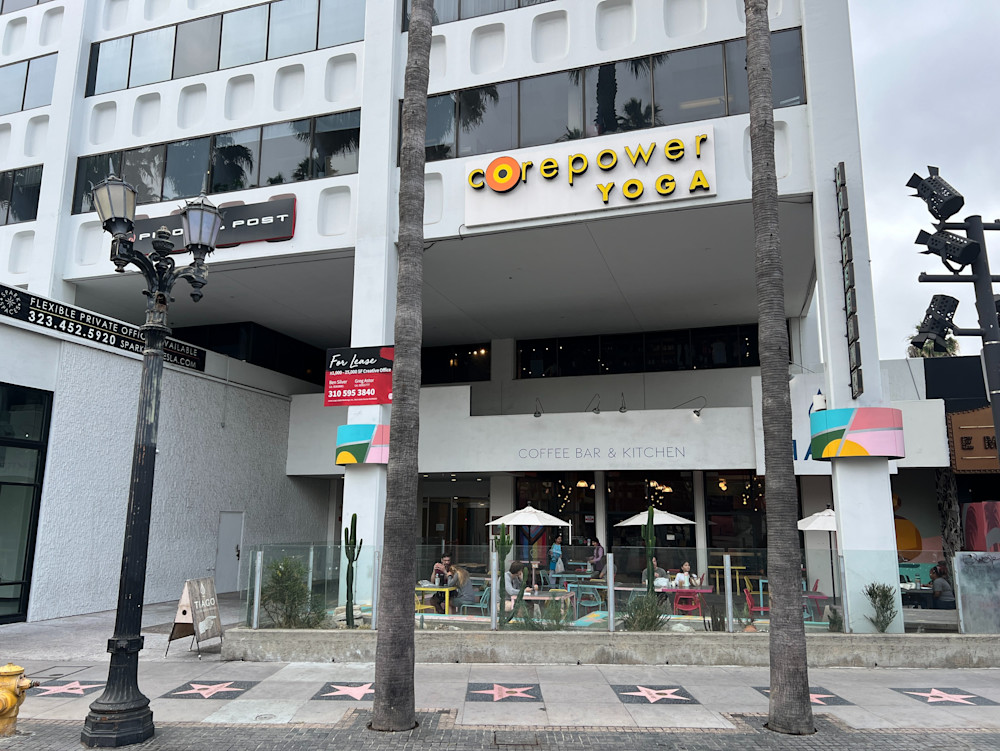 The CorePower Yoga sign on the upper floor of the building at Hollywood and La Brea, Walk of Fame stars set into the pavement below