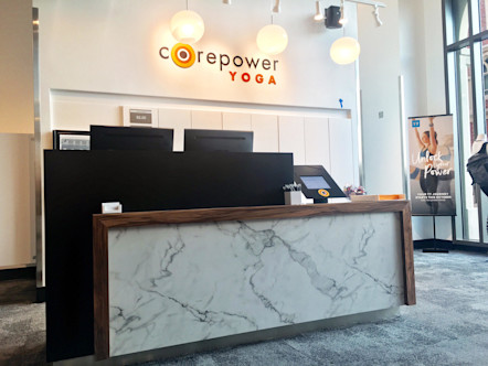White marbled and dark brown wooden front desk in front of a white wall with a large black lettered CPY sign