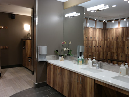 Brown wooden lockers reflected in the vanity mirror featuring an orchid and white sinks