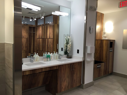 Bathroom area with a large wooden cabinet and white countertop dual sink with a large square mirror centered above