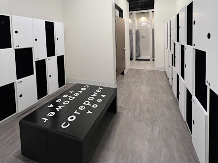 CorePower Yoga locker room area with a variety of different sizes of white lockers and cubby spaces with black CPY branded benches in the center