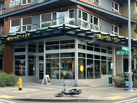 Windowed corner CorePower Yoga studio with a CPY sign on both sides underneath various balconies