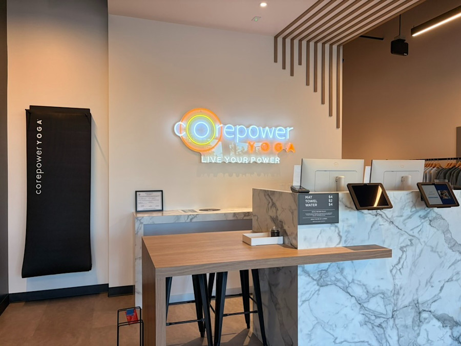 The reception desk at the studio, the CorePower Yoga logo lit on the wall behind it