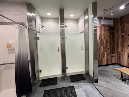 La Cumbre CPY locker room with two center showers with frosted class to the right of a brown wooden locker room area