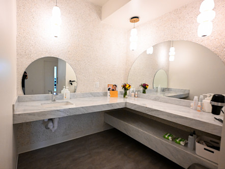 CPY Preston Hollow bathroom with large white marbled counter tops and large semi circle mirrors in the center of each vanity 