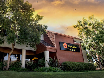 CorePower Yoga sign on the side of a red wood and tan stucco building with greenery surrounding
