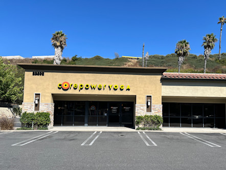Tan stucco building with a yellow CPY sign above a front wall of windows and a red Spanish-style roof