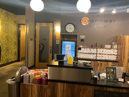 Wooden reception area hiding rows of towels and mats below a CorePower Yoga sign