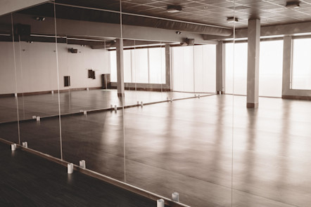 Beautiful studio space showered in natural light with floor to ceiling mirrors and a wooden floor