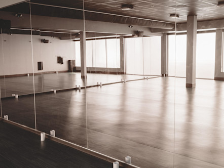 Beautiful studio space showered in natural light with floor to ceiling mirrors and a wooden floor
