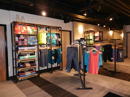 Bright retail merchandise including yoga mats, towels, leggings and tanks displayed in studio's lobby