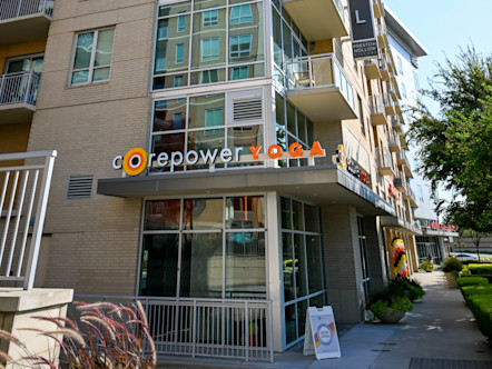 CorePower Yoga sign on the bottom floor on the corner of a large tan brick and windowed apartment building