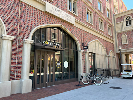 Small CorePower Yoga sign above a windowed entryway on a tan stone and red brick building