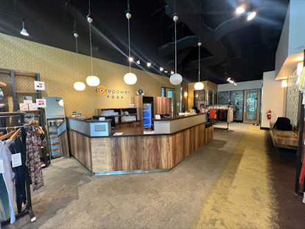 A CorePower Yoga sign touted on a neutral cream geometric wallpaper behind a wooden front desk
