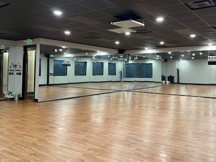 CorePower Yoga studio room with medium brown hardwood floors and mirrored front and side walls