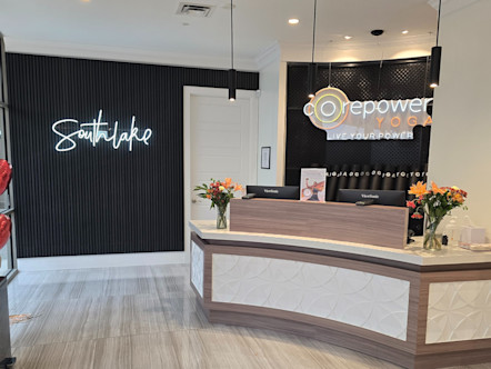 CPY Southlake front desk area with a cursive text neon Southlake sign on a textured black wall