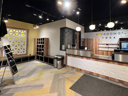 A large metal, wooden, and floral tiled printed front desk with a cubby and seating area to the left and chevron printed carpet