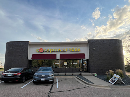 Stand-alone CorePower Yoga building with burgundy awnings and yellow CPY signage above