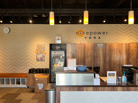 Neutral colored chevron wallpaper behind large wooden cabinets and a CPY sign above in front of a wooden and white chevron tiled front desk