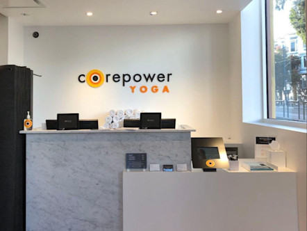 CPY sign on a white wall behind white and marbled front desks with a large window to the left