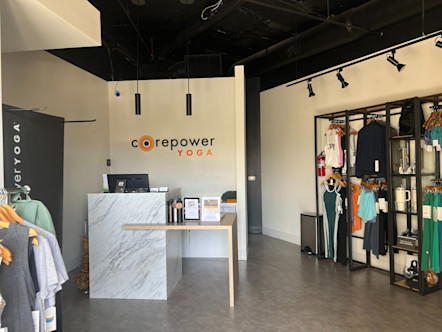 White marble front desk in front of a CorePower Yoga sign on a white wall with retail inventory on both walls adjacent