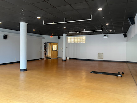 CPY studio room with light tannish-yellow hardwood floors with a single CorePower Yoga instructor mat in the front center of the room